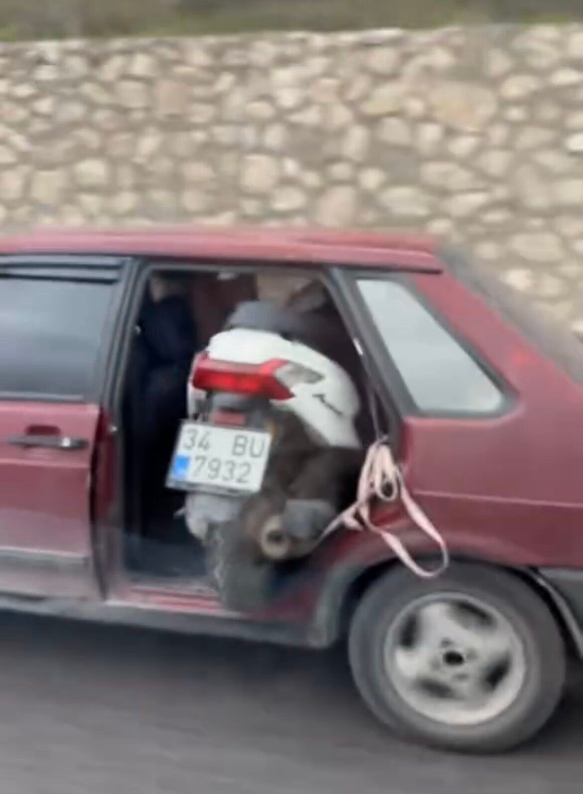 Bursa'da kapısız otomobiliyle motosiklet taşıyan bir sürücü, cadde boyunca ilerleyerek