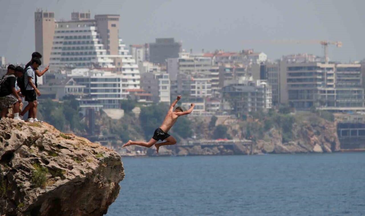 Antalya'nın Konyaaltı Sahili'nde gençler, 30 metrelik falezlerden denize atlayarak adrenalin