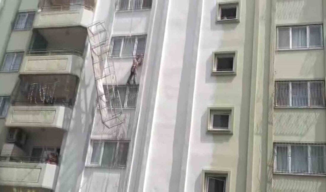 Adana'nın Yüreğir ilçesinde dış cephe boyası yapan işçi, iskelesinin halatının