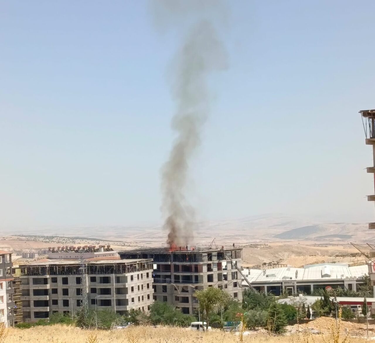 Adıyaman'ın Besni ilçesindeki inşaat halindeki bir binanın çatısında çıkan yangın,