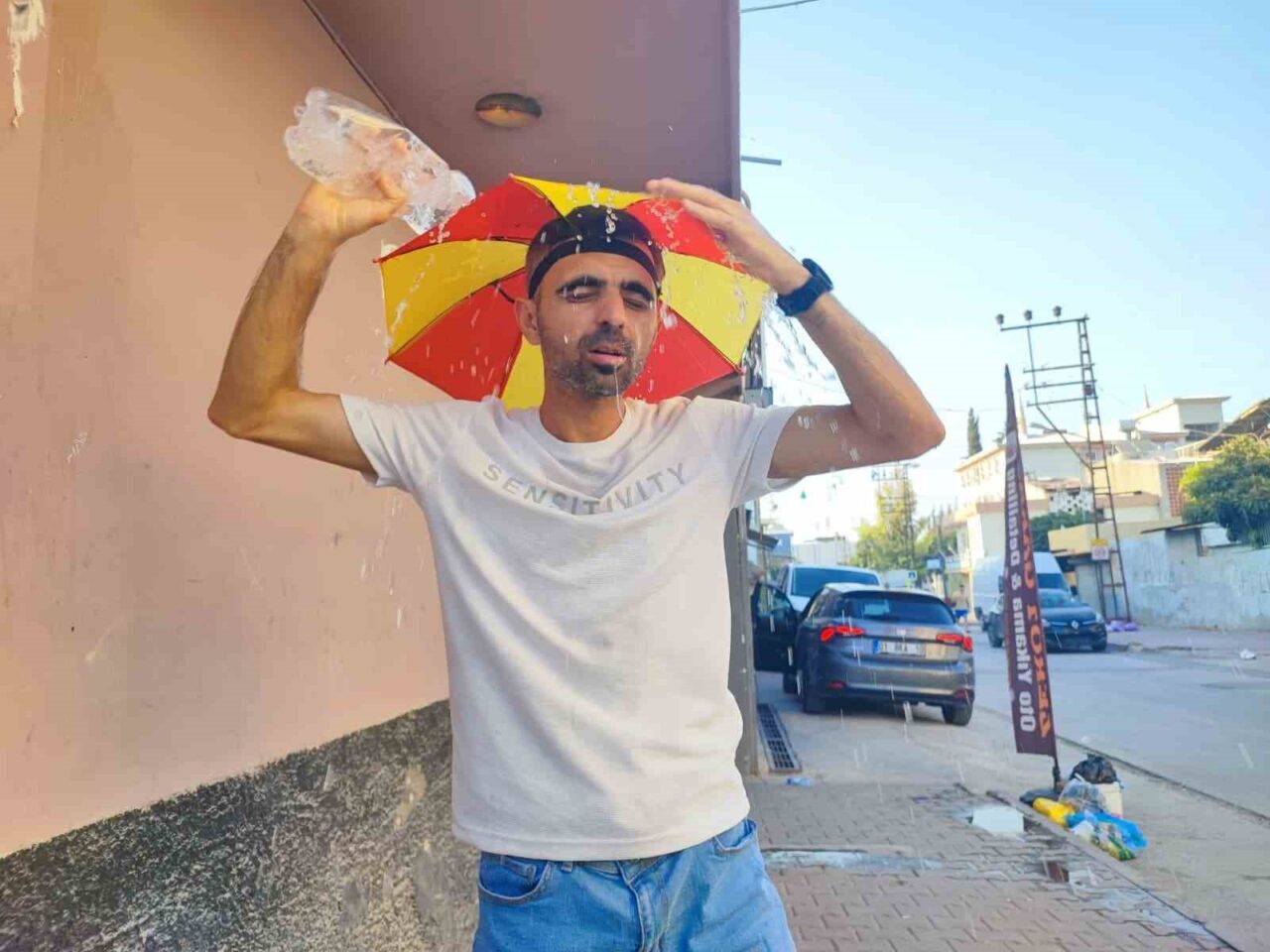 Adana'da sıcaklık 58 dereceyi aşınca, Mesut Akpınar kafasına şemsiye takarak