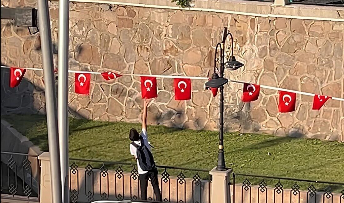 Çankırı'da bir çocuk, rüzgar nedeniyle ters dönen Türk bayraklarını düzeltti.