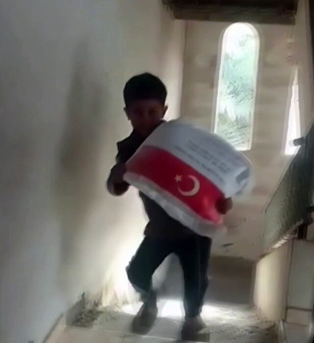 Gazze Şeridi'nde bir Filistinli çocuk, Türkiye'den gelen un yardımını taşırkenki