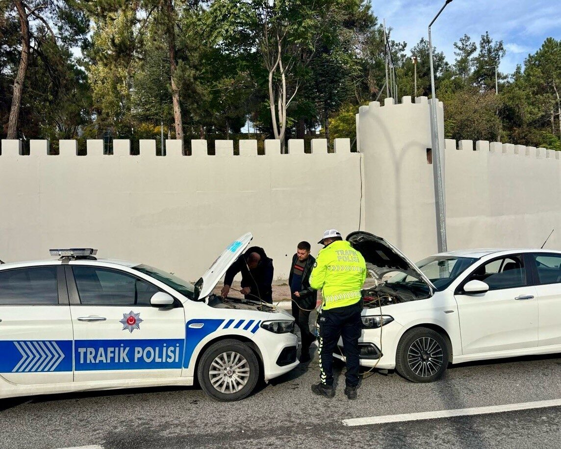 Bilecik'te trafik polisi, arızalanan bir otomobile akü takviyesi yaparak hem