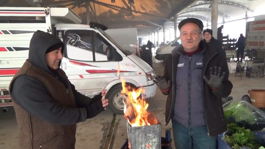 Kütahya’daki pazarcılar, soğuk havadan korunmak için tezgahlarının yanında ateş yakıyor.